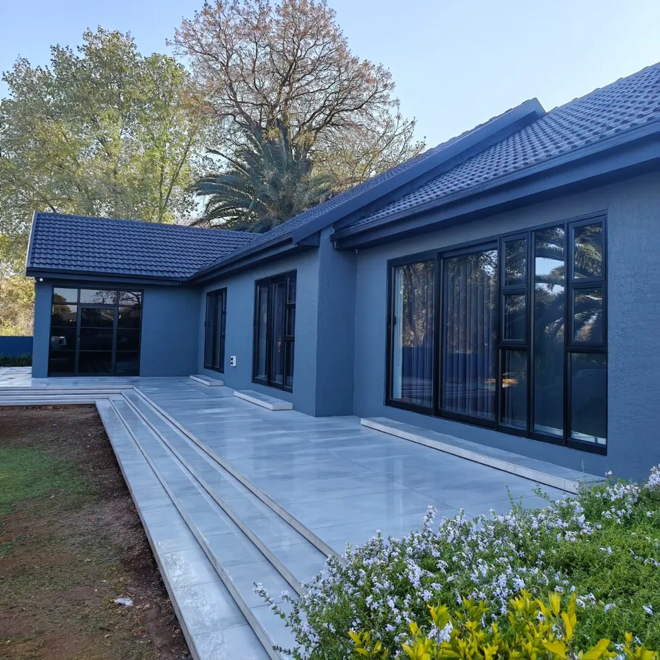 Finished renovation: dark blue house with black-framed windows and a pale tiled terrace and steps