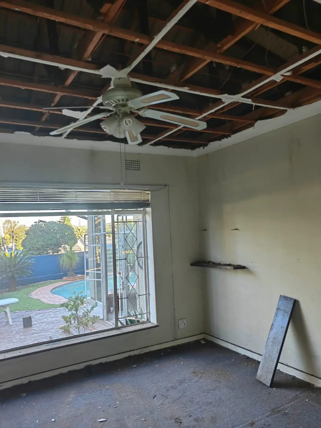 Bedroom with the old ceiling pulled down to the roof timbers and a steel window onto the pool