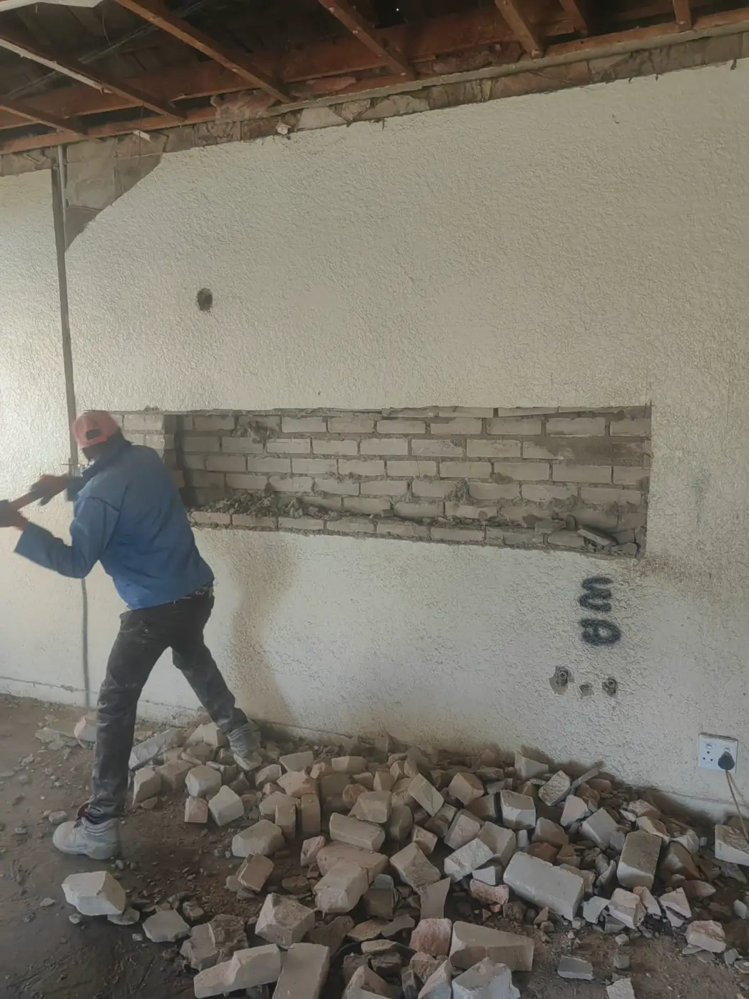 A builder breaking out brickwork to make a new window opening