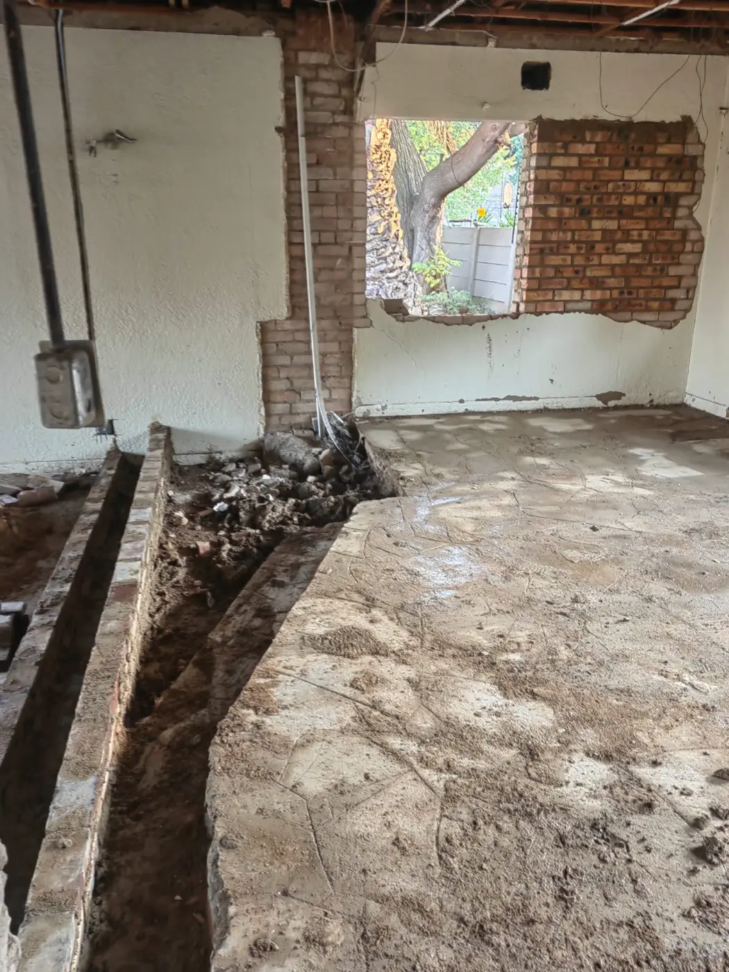 Floor trenches cut for new plumbing in an open room