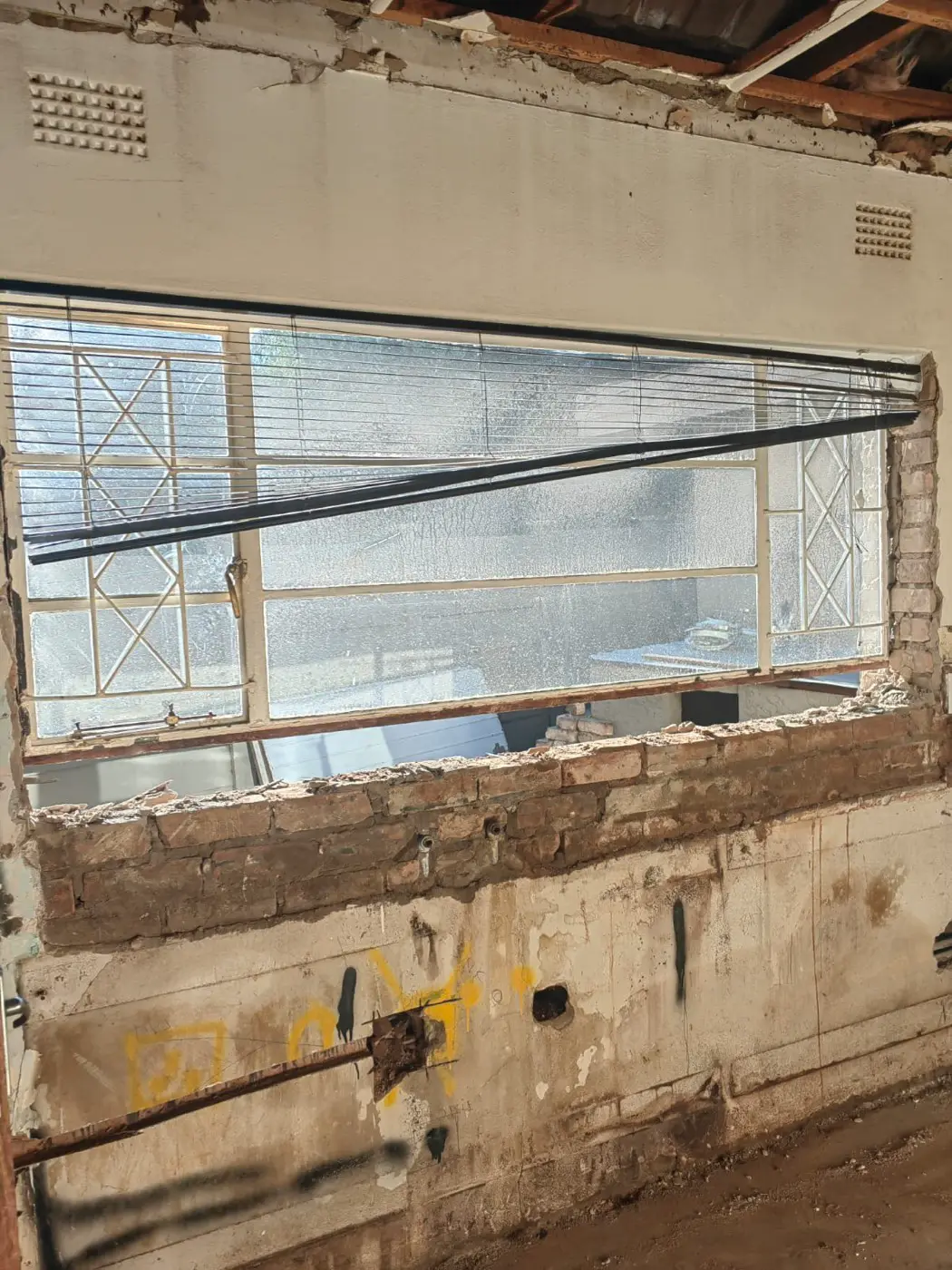 An old window opening cut wider, with the brickwork below exposed