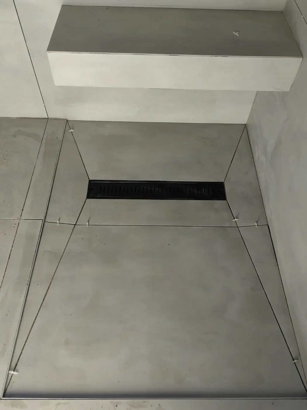 A walk-in shower floor screeded to fall towards a long drain