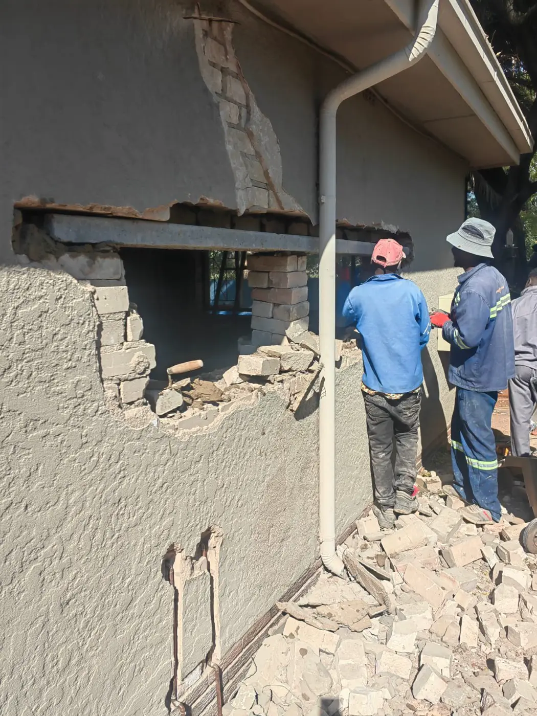 Builders fitting a new concrete lintel over a widened opening in an outside wall