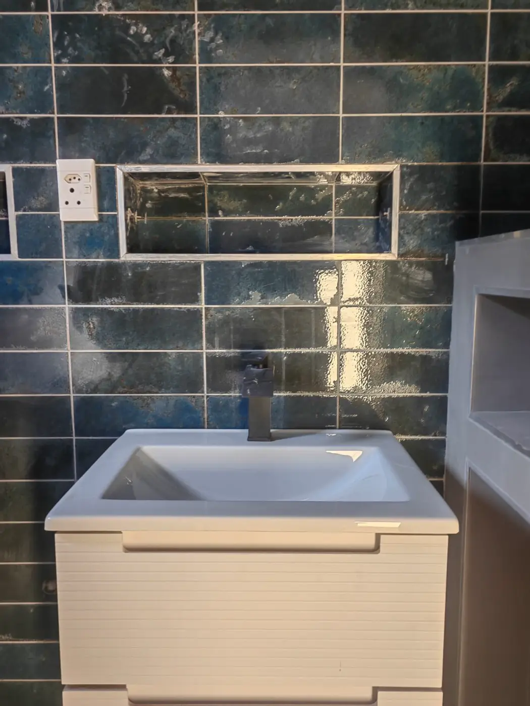 Close-up of a white basin and black tap against blue tiles