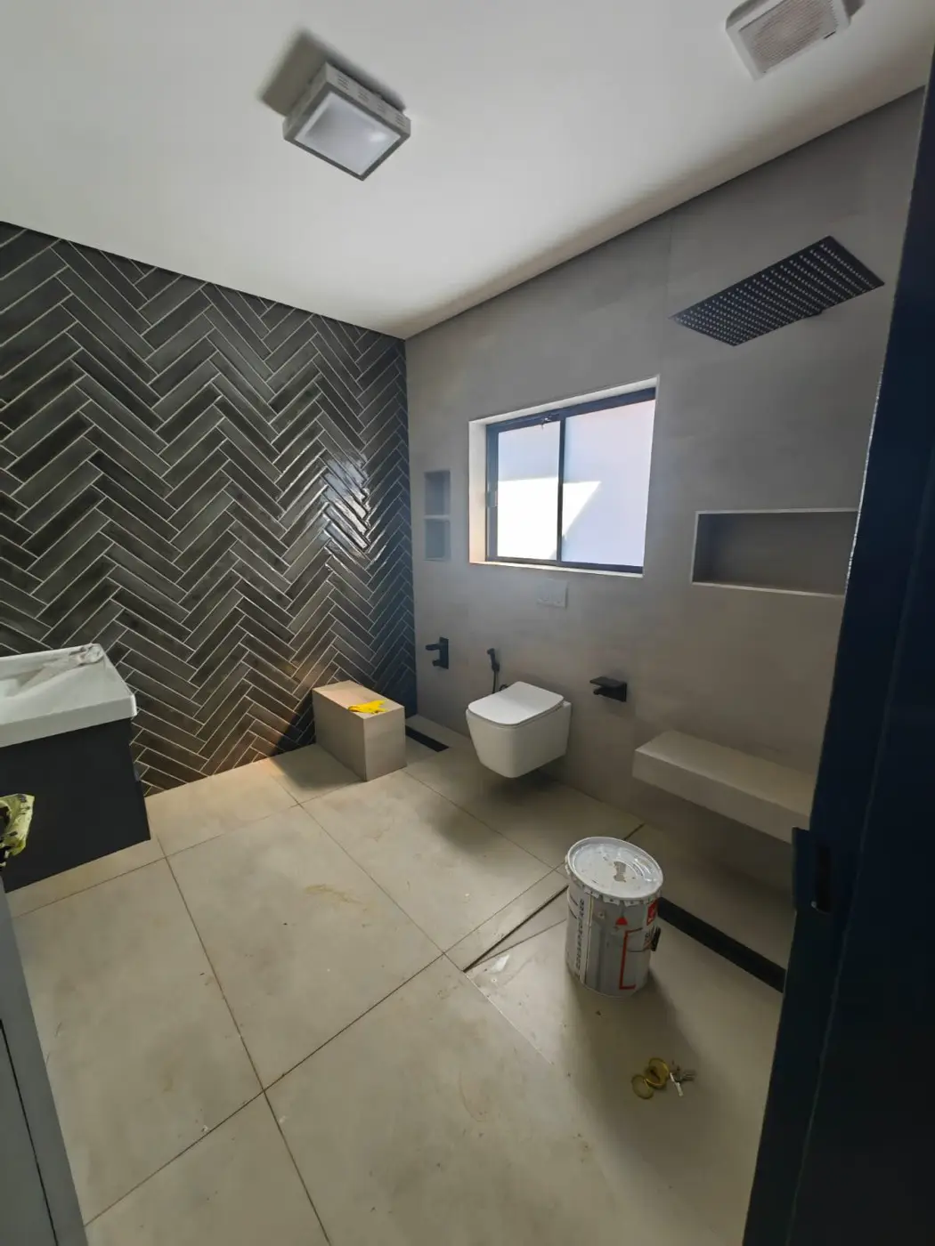 Bathroom with a black herringbone feature wall and large pale floor tiles