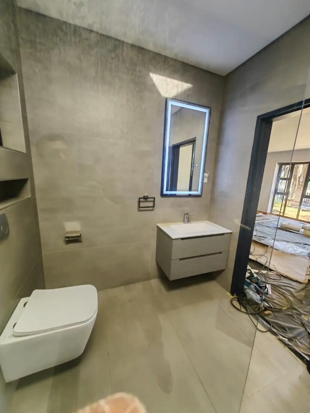 Bathroom with a lit mirror and a floating vanity on pale grey walls