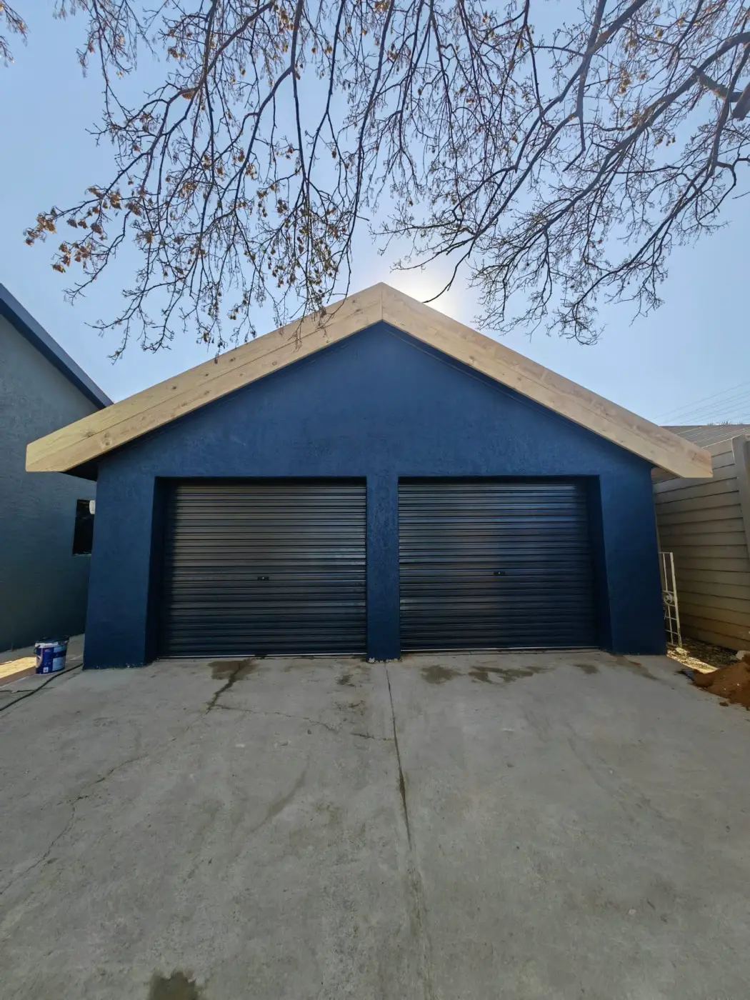 The double garage with new roller doors and a timber-clad gable