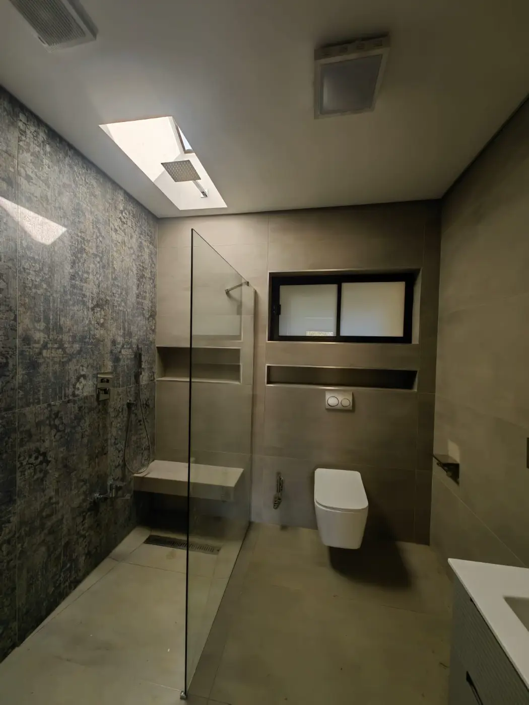 Walk-in shower with a stone-look feature wall, a niche and a glass screen