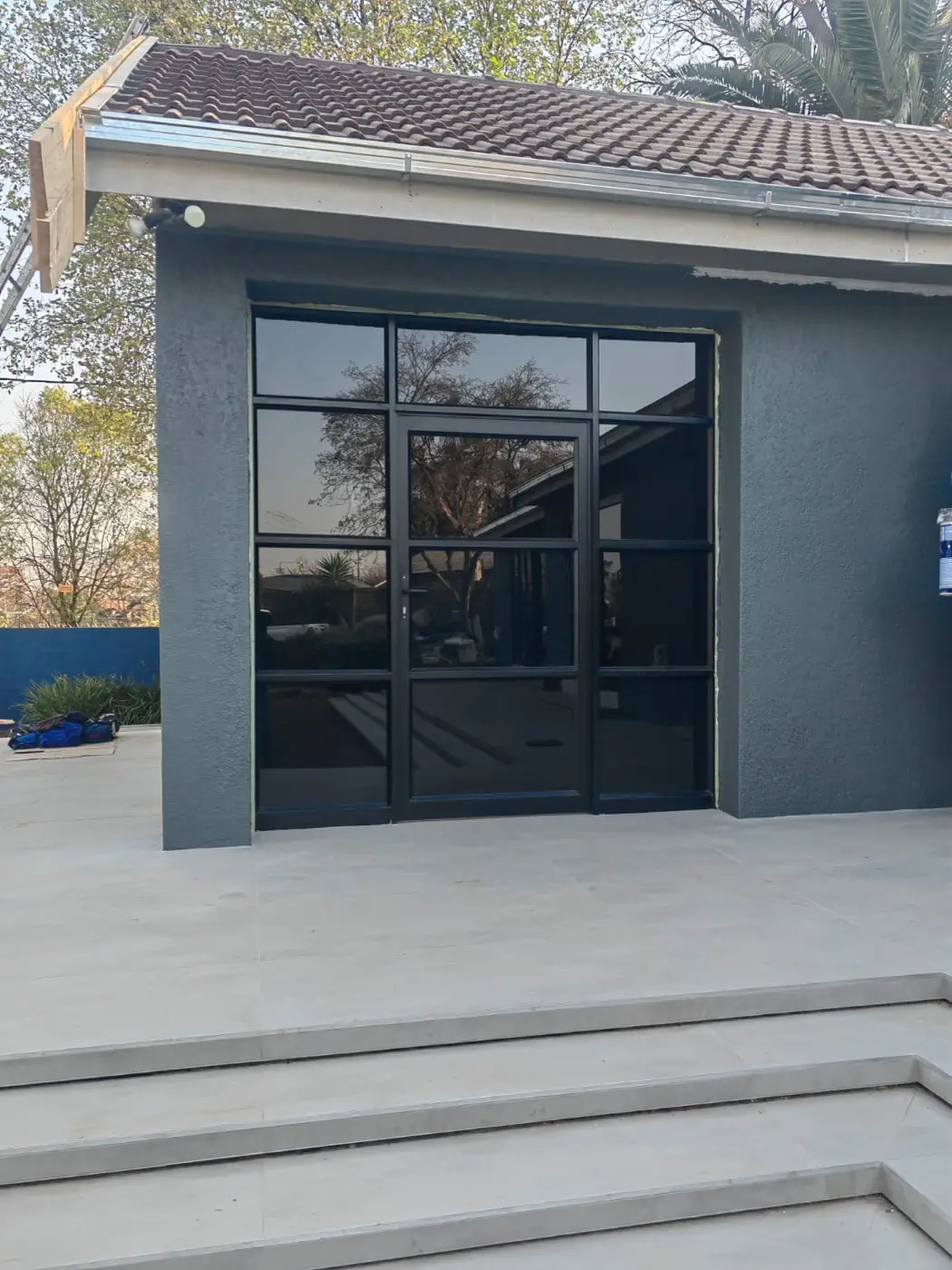 A black steel-and-glass door set into the dark blue wall