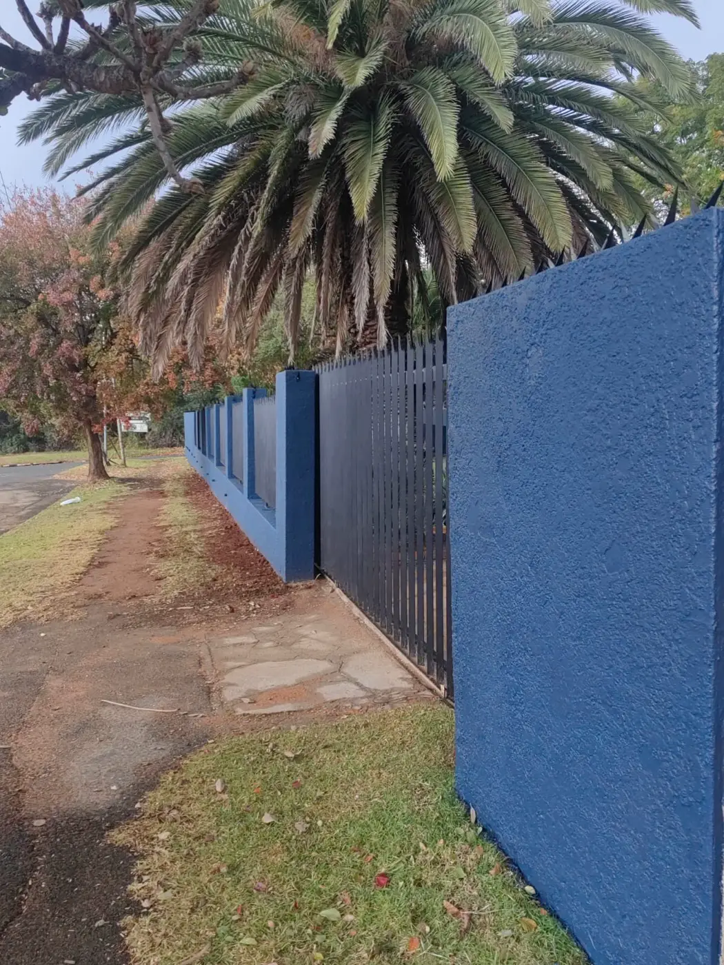 A dark blue pillar beside the steel palisade gate